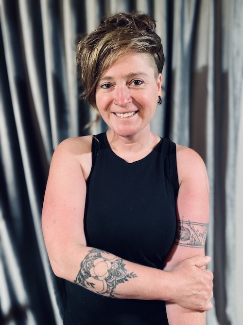 Photo of Katie Sawicki smiling at the camera. She is standing in front of a grey background.